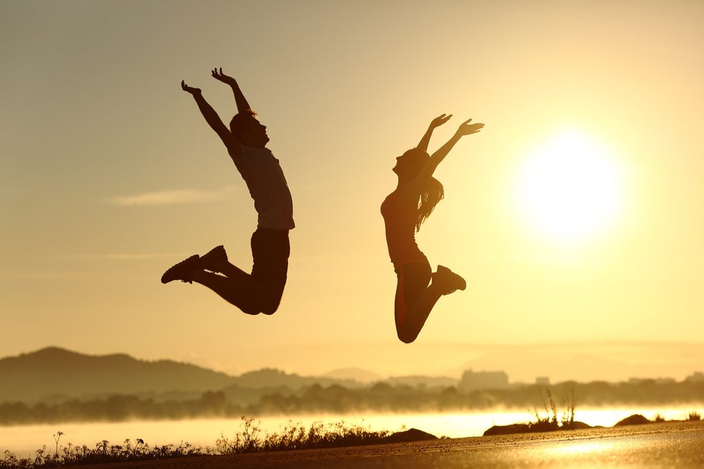 Vitalität & Gesundheit fitness couple jumping happy at sunset